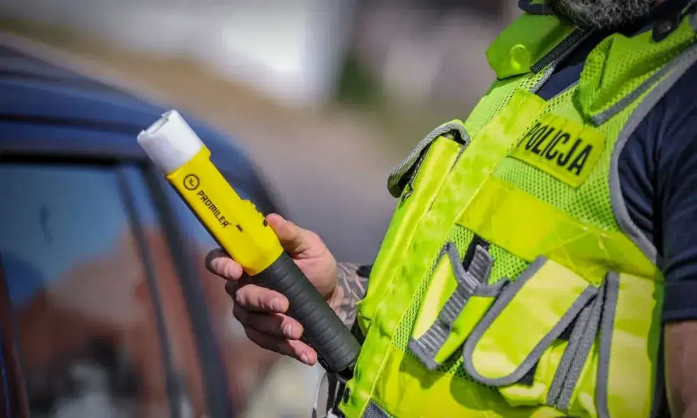 policjant przy drzwiach z alkomatem